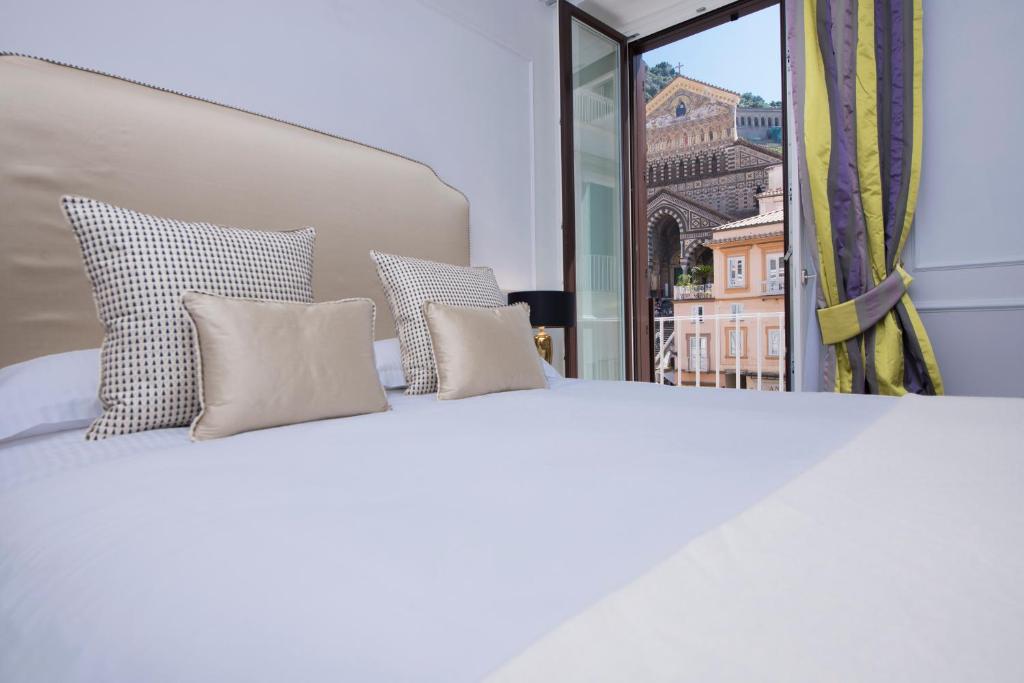 阿马尔菲La Bambagina的一张带四个枕头的白色床和窗户