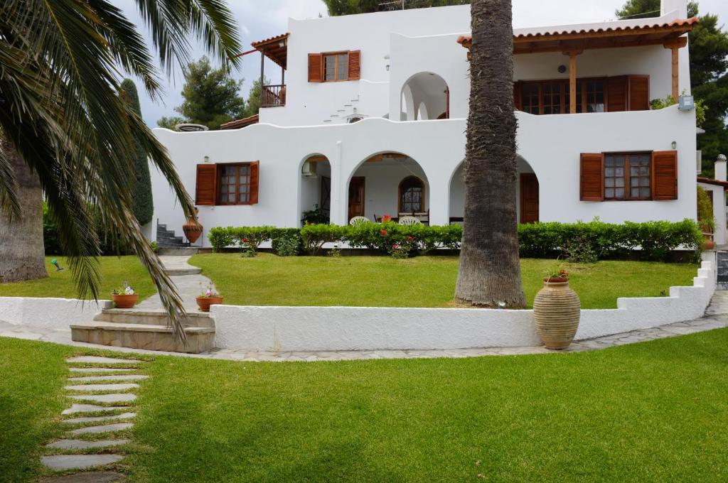 波利蒂卡Villa Pefkias的院子里有棕榈树的白色房子