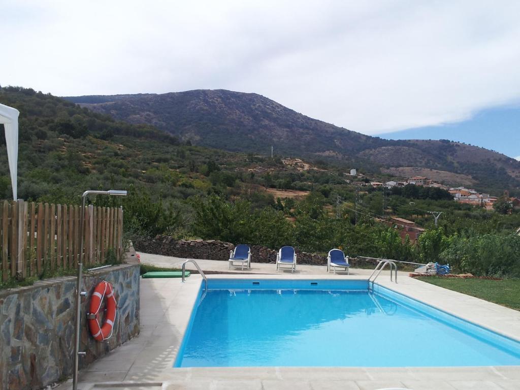 Casas del MonteApartamentos rurales Manolo的一个带两把椅子的游泳池和一个山