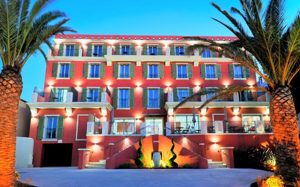 利勒鲁斯Hôtel Liberata & Spa的一座大型红色建筑,前面有棕榈树