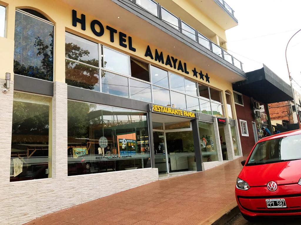 伊瓜苏港Hotel Amayal的酒店前方停有一辆红色的汽车,