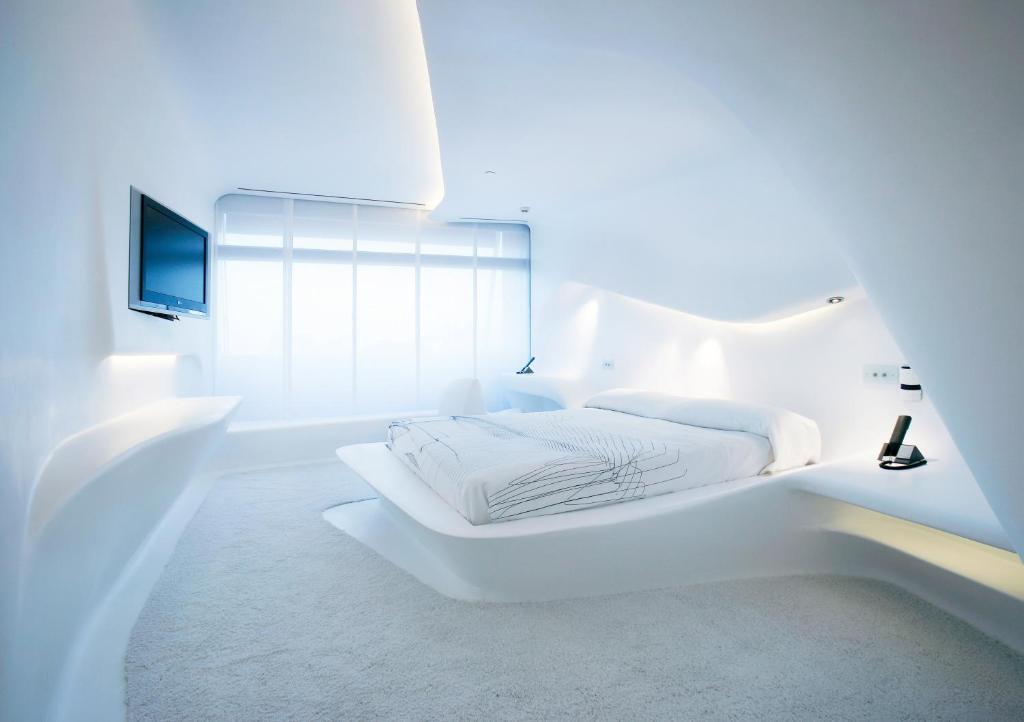 马德里美洲门酒店的一间白色卧室,配有床和电视