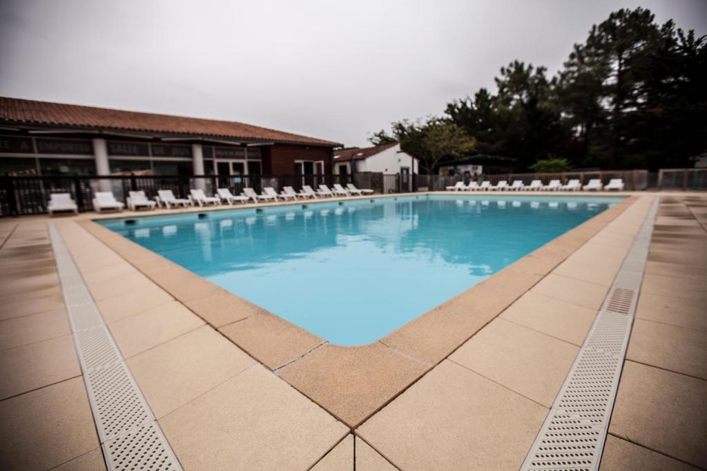 圣特罗让莱班Village Vacances Passion Les Bris的一个带椅子和蓝色水的大型游泳池