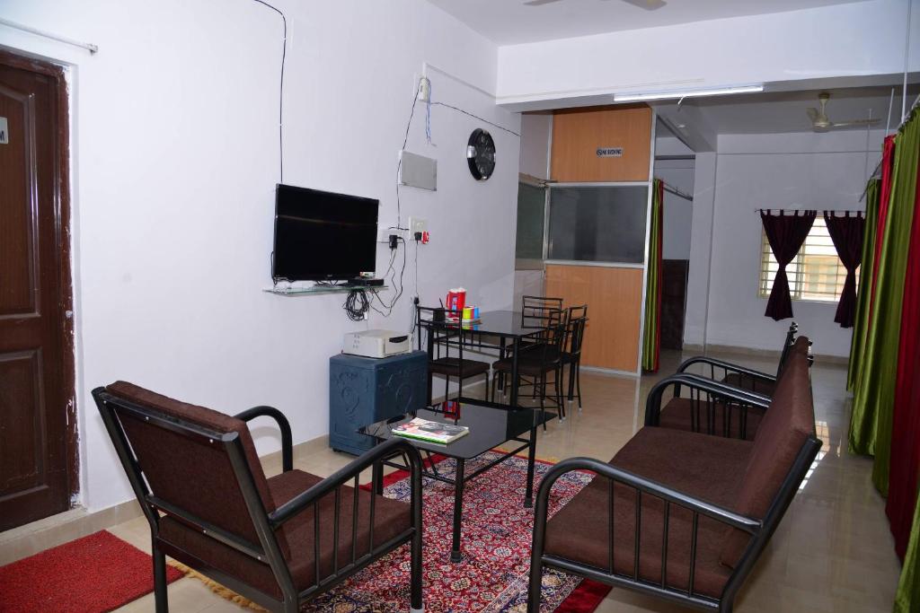 布巴内什瓦尔Tranquil Hospitality的客厅配有椅子、桌子和电视