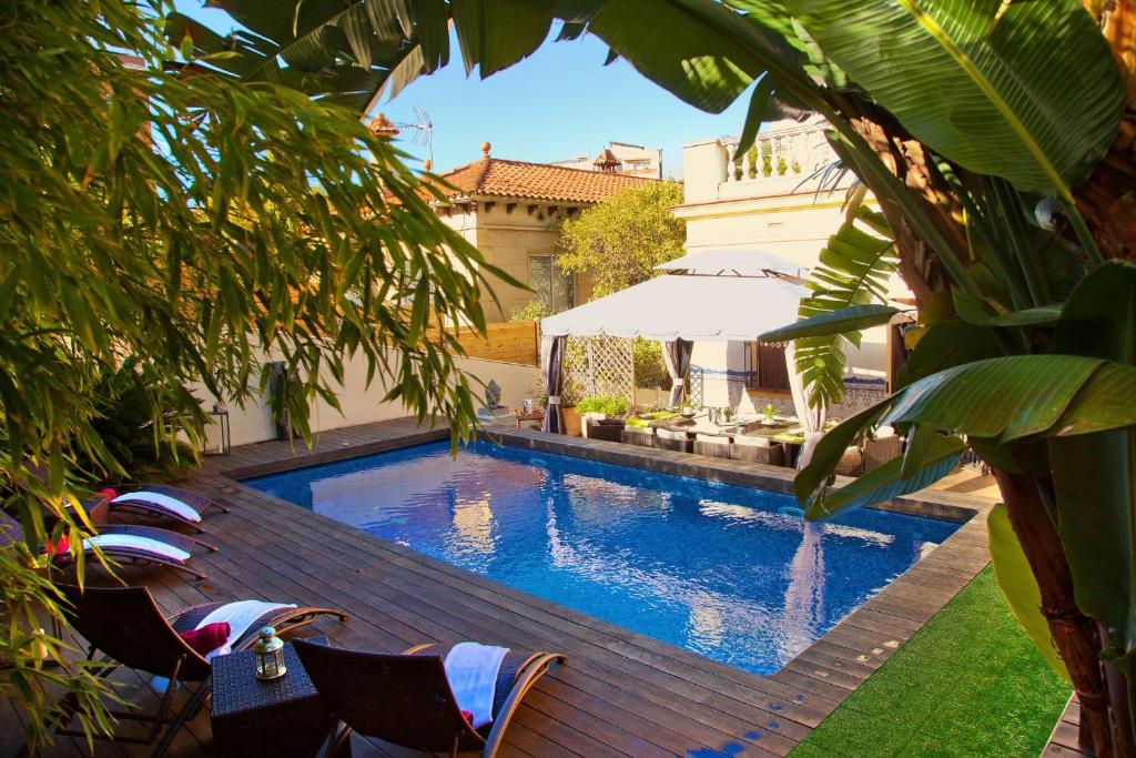 巴塞罗那巴塞罗那维多利亚别墅酒店的庭院内的游泳池配有椅子和遮阳伞