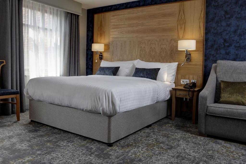 诺丁汉华美达诺丁汉市中心酒店的一间卧室配有一张大床和一把椅子