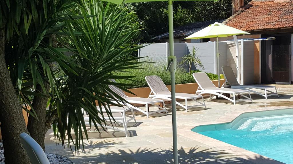 勒博塞库奇叶酒店的一组椅子和一把遮阳伞,位于游泳池旁
