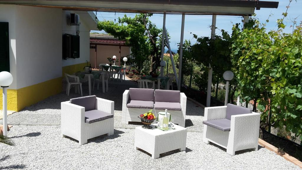 特罗佩阿B&B del Sole Tropea的庭院配有白色的椅子、桌子和桌椅