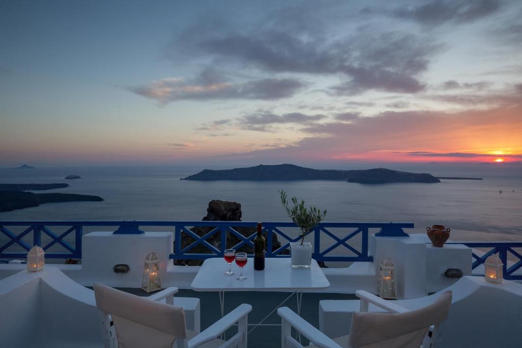 易莫洛林Annio Santorini的一张桌子和椅子,享有海洋日落美景