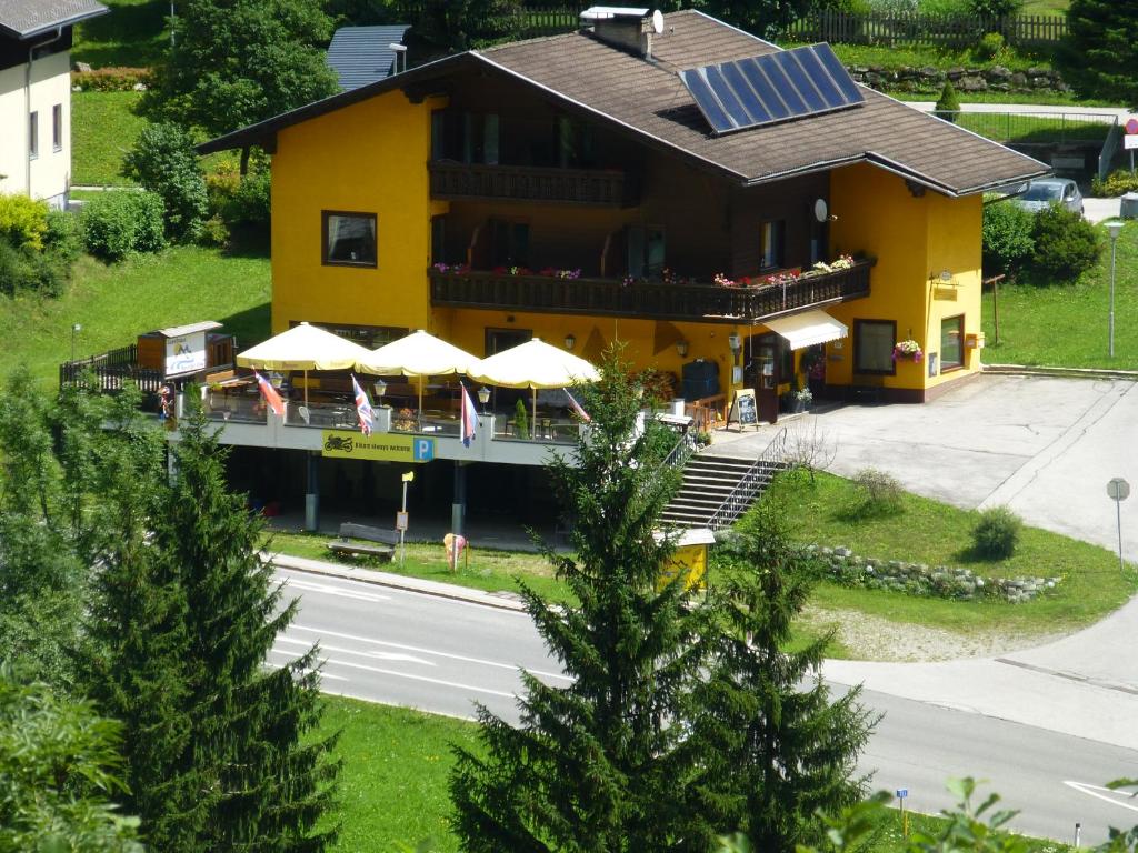 大基希海姆Guesthouse Mountain View的黄色建筑,带雨伞的餐厅