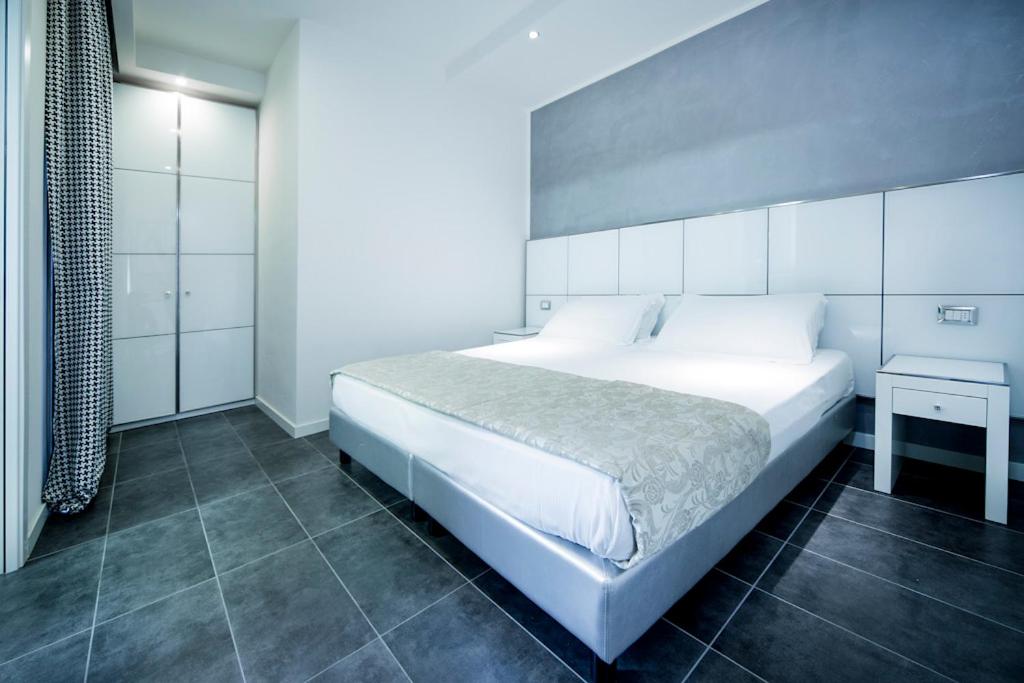 里米尼氛围套房酒店的卧室配有一张白色的大床和一张桌子