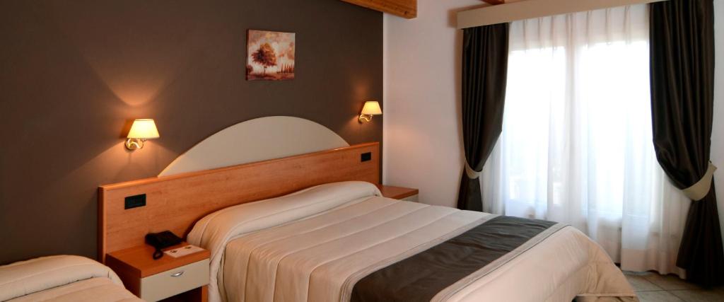 巴斯蒂亚乌姆布拉Hotel Il Cammino Di Francesco的酒店客房设有两张床和窗户。