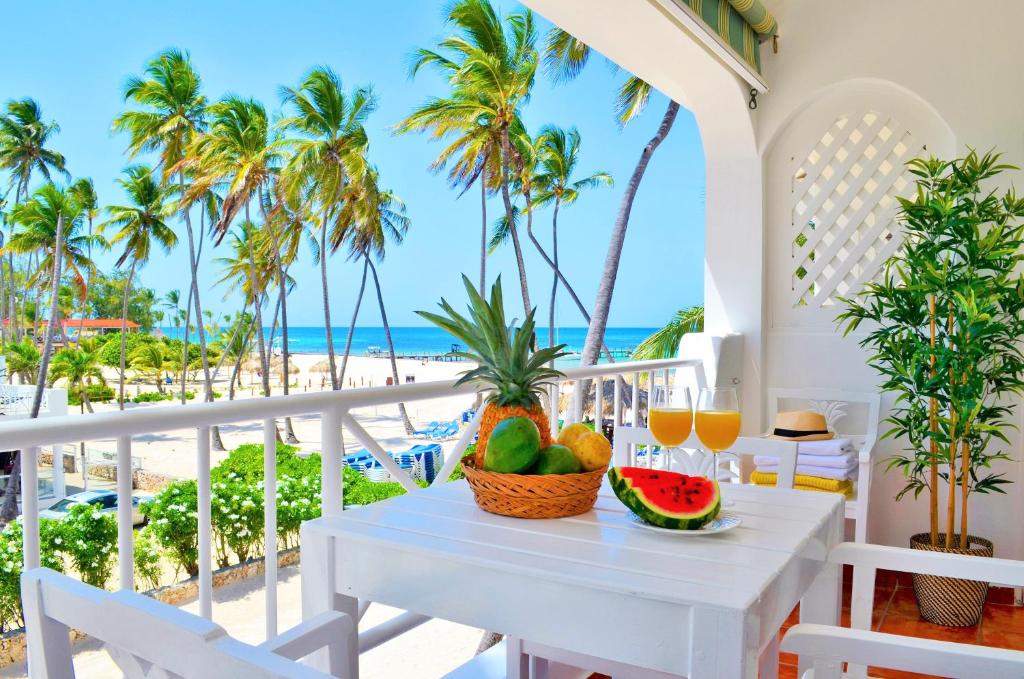 蓬塔卡纳Beach Villas & Apartments Larimar的俯瞰海滩的阳台的桌子上摆放着水果和果汁
