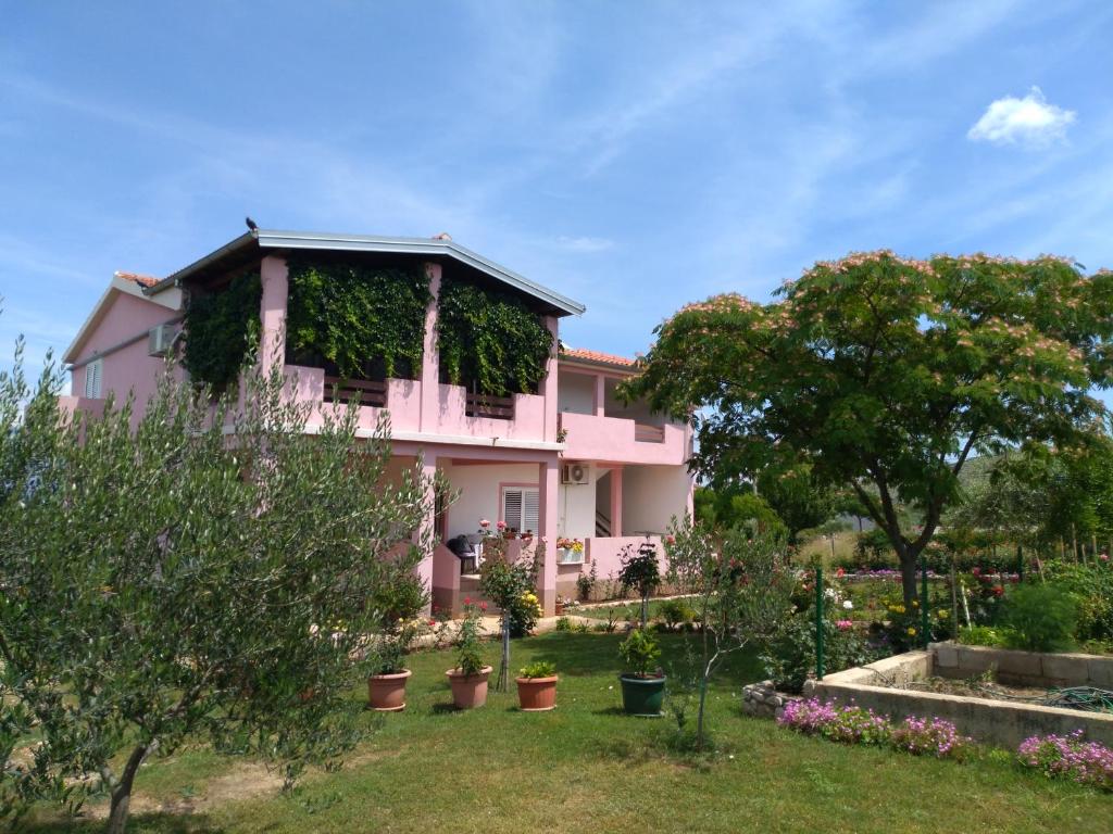珀塞达耶Apartment Ema的院子里有植物的粉红色房子
