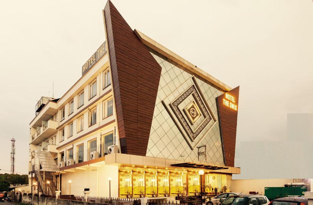 德拉敦Hotel The Onix的前面有停车位的建筑