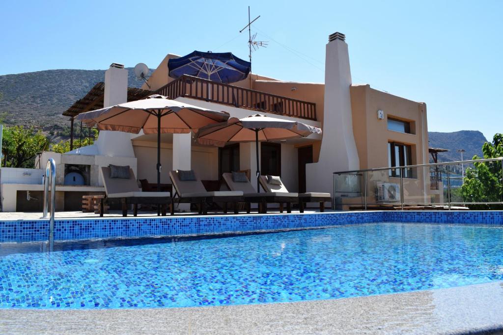 赫索尼索斯Ida villa的别墅 - 带带椅子和遮阳伞的游泳池