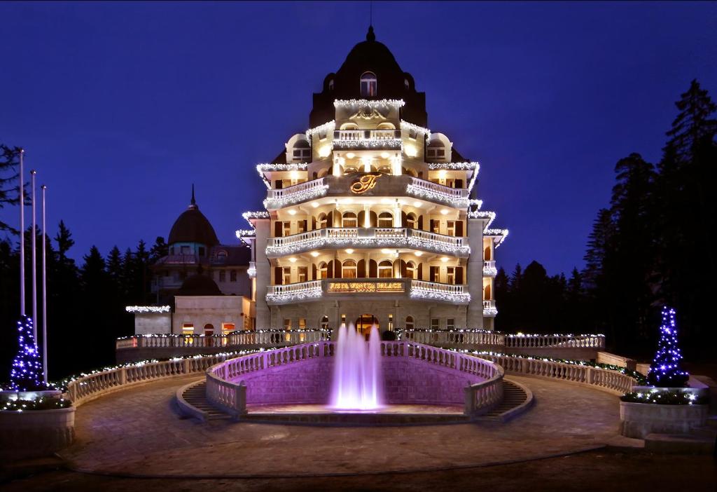 波罗维茨Festa Winter Palace Hotel的一座建筑,在晚上前方有一个喷泉