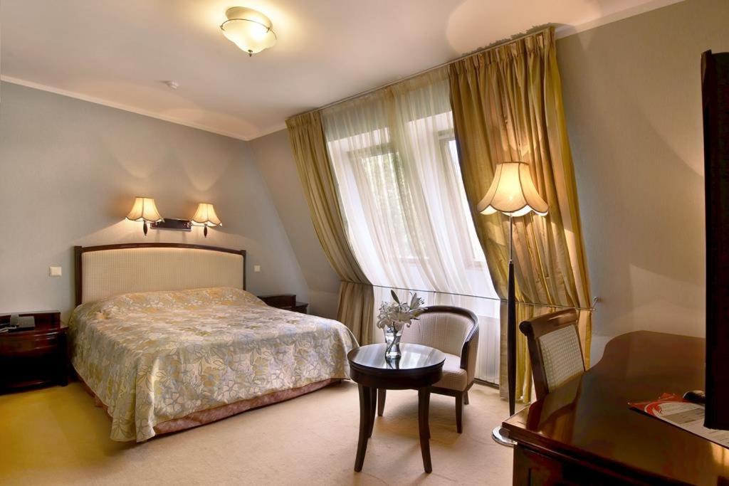 奥布宁斯克Greenway Park Hotel的一间卧室配有一张床、一张桌子和一个窗户。