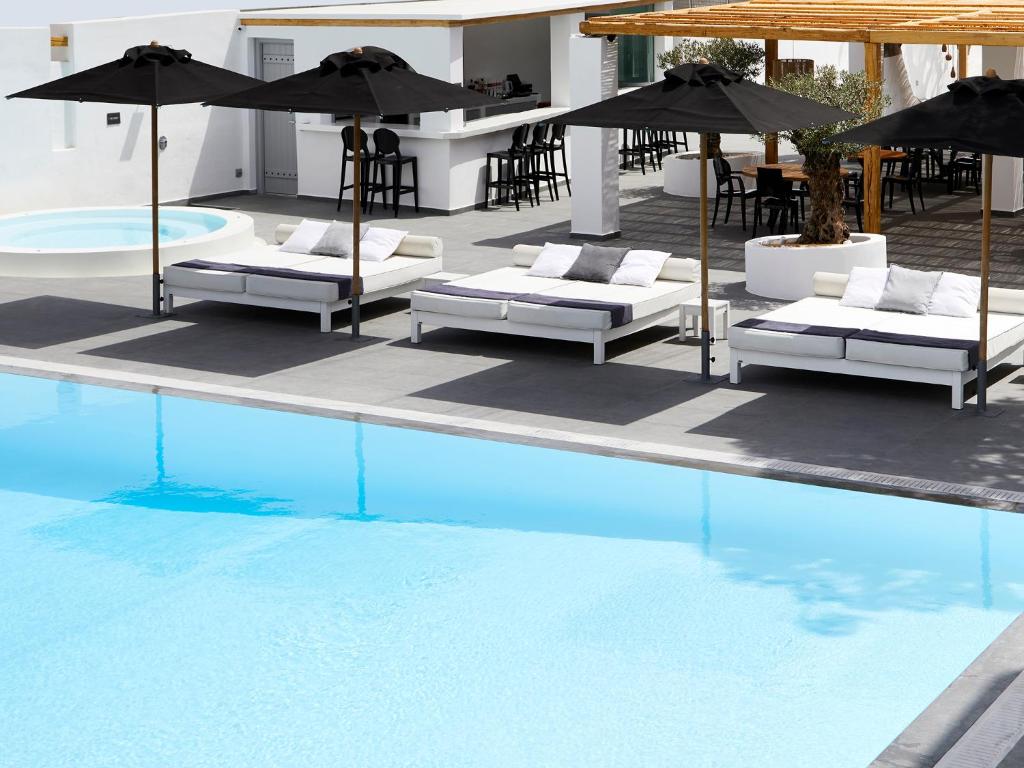 费拉卡利斯提酒店及套房的游泳池旁的游泳池配有椅子和遮阳伞