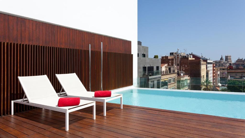 巴塞罗那巴塞罗那伯爵酒店的阳台配有两把椅子,大楼内设有一个游泳池