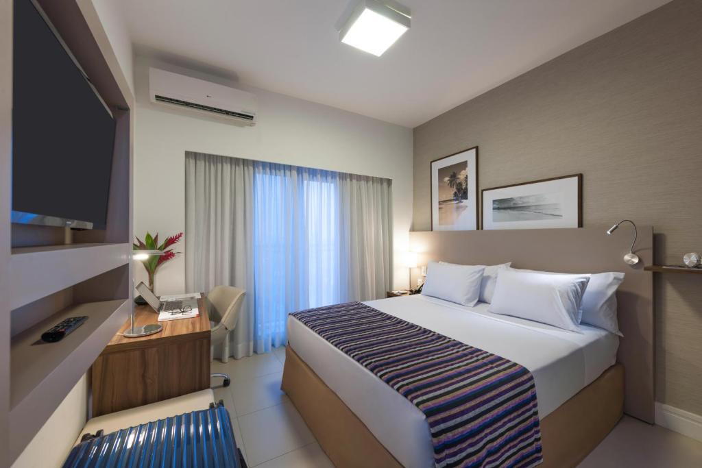 卡希亚斯公爵城Matiz Multi Suites的酒店客房配有一张床、一张书桌和一台电视。