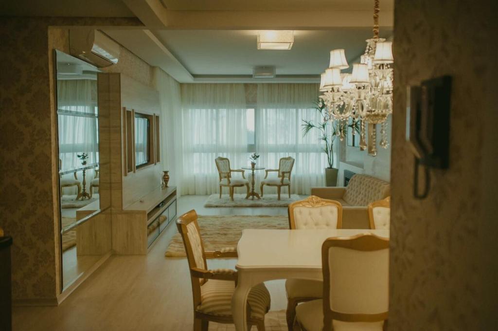 格拉玛多Altos da Bela Vista Gramado centro locação de temporada的用餐室以及带桌椅的起居室。