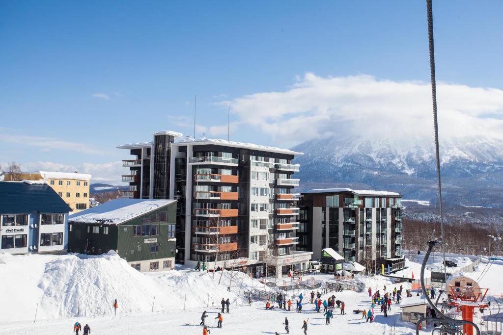 二世古阿尔卑斯山岭酒店的一群人站在滑雪场的建筑前