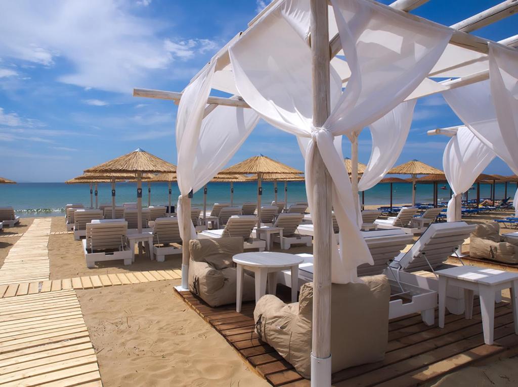 克里希阿克提阿玛丽利斯海滩酒店的海滩上的餐厅,配有椅子和遮阳伞