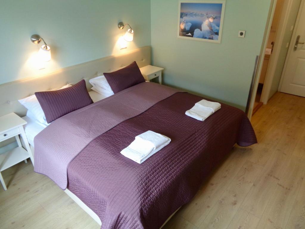哈利哈利乡村酒店的一间卧室配有一张紫色床和两条毛巾