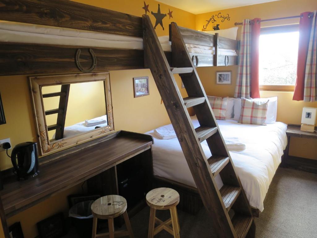 米尔顿凯恩斯Adventurer's Village Milton Keynes的一间卧室配有一张带镜子的双层床和两张凳子