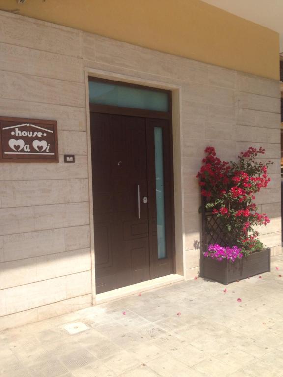 滨海波利尼亚诺House Mami的一座有黑色门和花卉植物的建筑