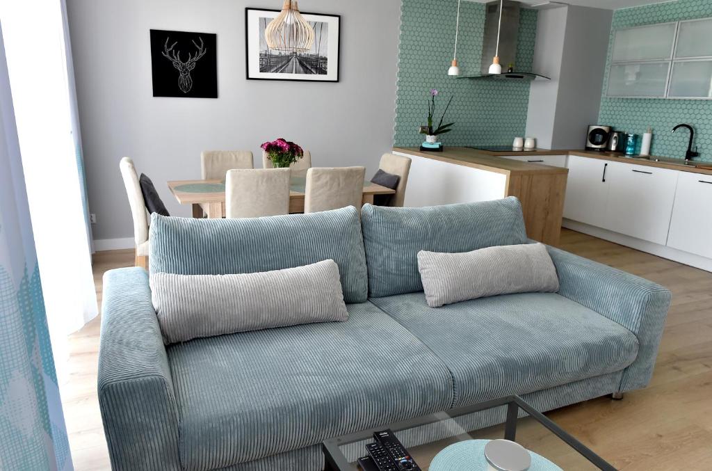 科希切日纳Apartament Turkus的一间带蓝色沙发的客厅和一间厨房