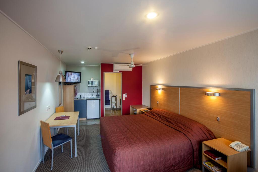 新普利茅斯兰德马克庄园酒店的一间带一张床和一张书桌的卧室和一间厨房
