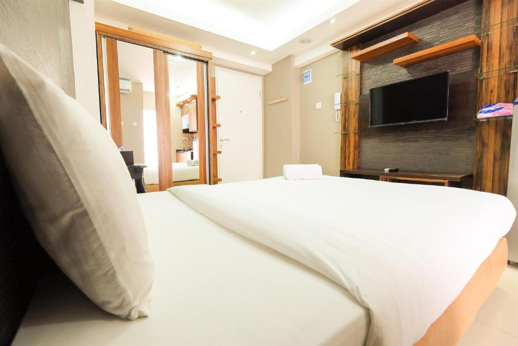 雅加达Simple Studio Bassura City Apartment By Travelio的卧室配有白色的床和平面电视。