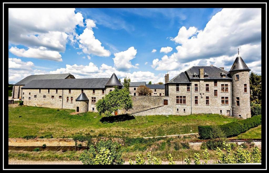 LaneffeFerme Château de Laneffe的一座大城堡,位于一座建筑前的草木山丘上