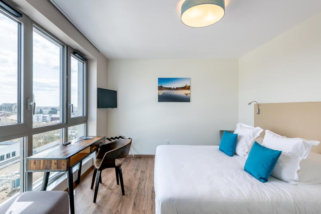 波尔多All Suites Bordeaux Marne – Gare Saint-Jean的卧室配有一张床、一张书桌和窗户。
