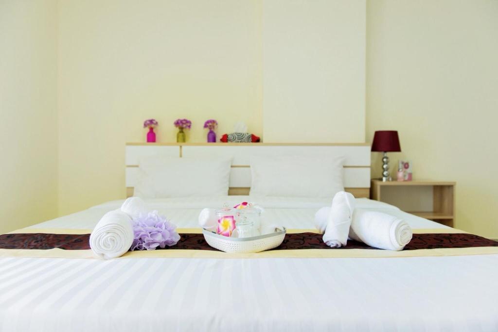 曼谷Be My Guest 36的一张带毛巾的白色床和一个带一碗化妆品的托盘