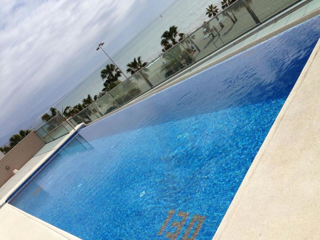 滨海罗克塔斯Piso 1a Linea piscina 3D的一座种植了棕榈树和大海的大型蓝色游泳池