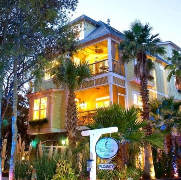 富丽海滩Water's Edge Inn - Adults Only的一座棕榈树大房子前面