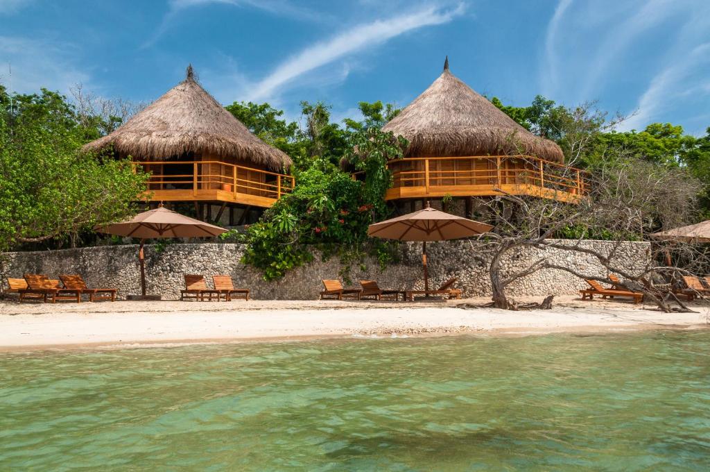 巴尔Hotel Las Islas的海滩上的度假村,配有椅子和遮阳伞