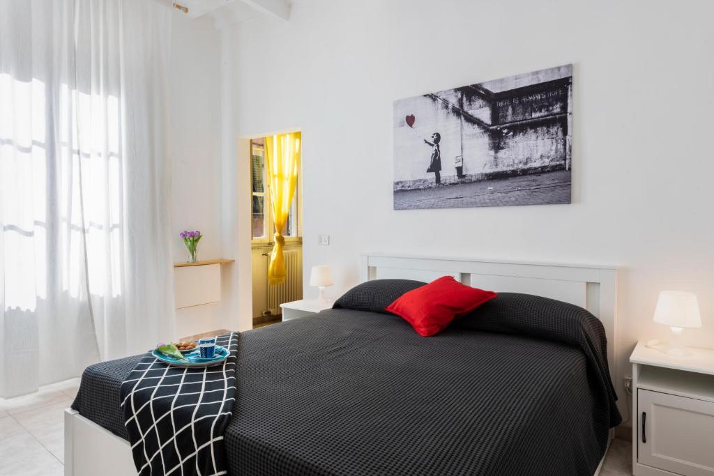 比萨La Lupa Capitolina (100 meters from the tower)的卧室配有黑色和白色的床和红色枕头