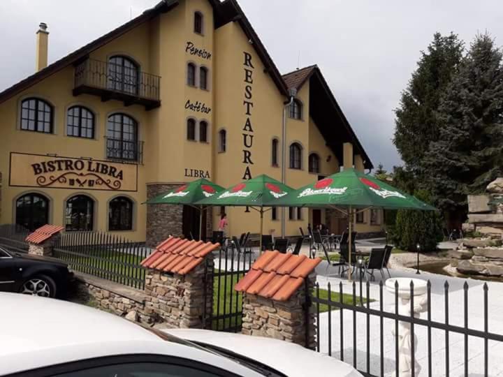 VelešínPension Libra的大楼前的一间餐厅,配有绿伞
