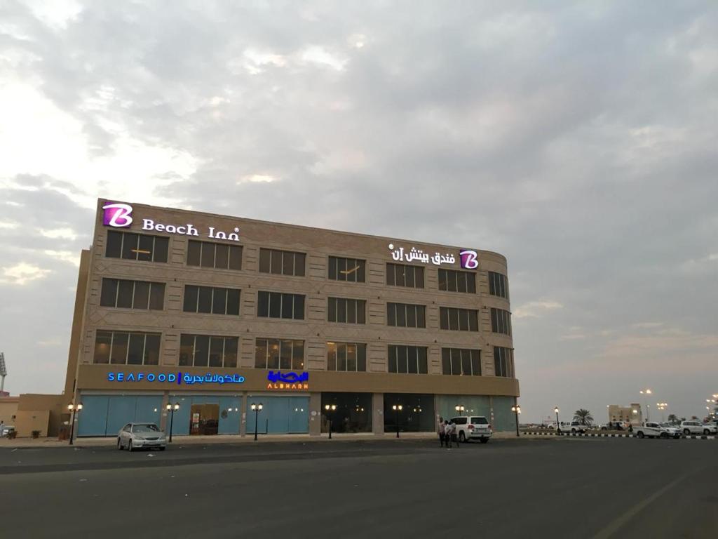 Al QunfudhahBeach Inn的一座大型建筑,前面设有停车场