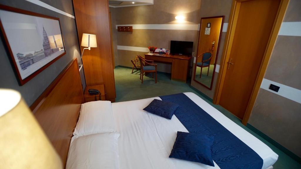 特尔尼郁金香经典酒店的一间卧室配有一张带蓝色枕头的床和一张书桌
