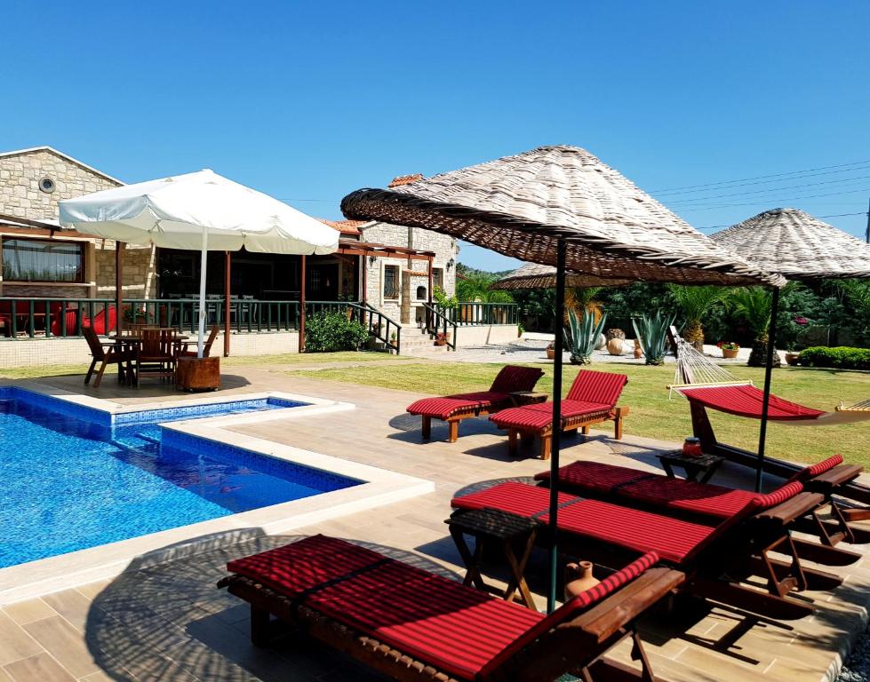 达特恰Pension Villa Kizlan Ova的毗邻度假酒店的带椅子和遮阳伞的游泳池