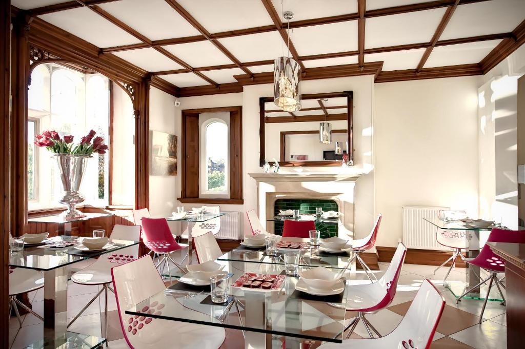 戈德尔明Godalming Hotel Guest House的一间带桌椅和壁炉的用餐室