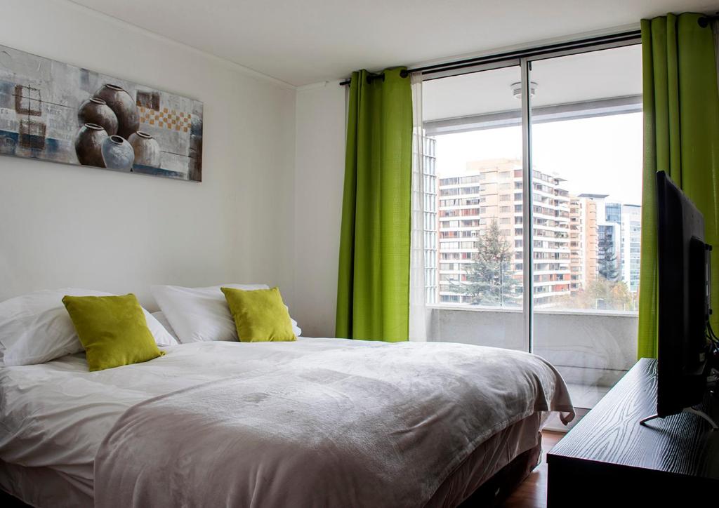 圣地亚哥Kennedy Apartments Los Militares的一间卧室配有一张带绿色窗帘的床和窗户。