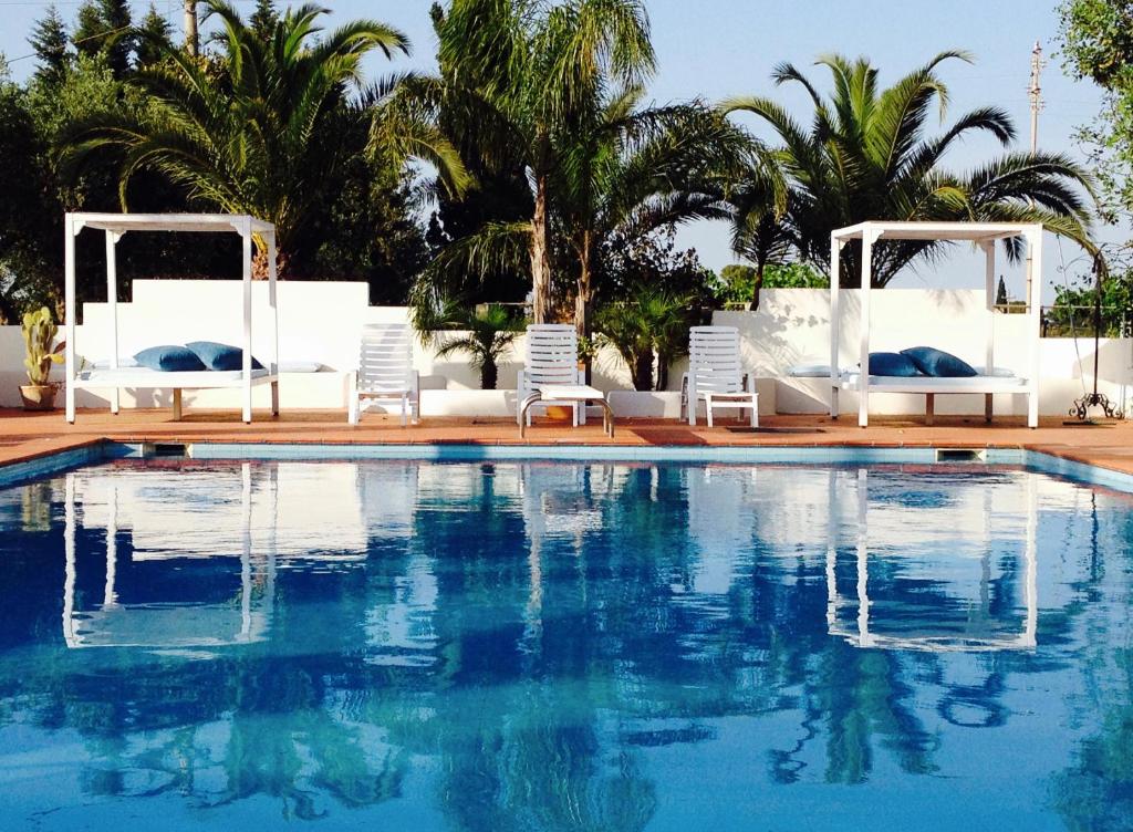 加拉托内坎皮拉提尼农家公寓式酒店的一个带白色椅子的游泳池和一个游泳池