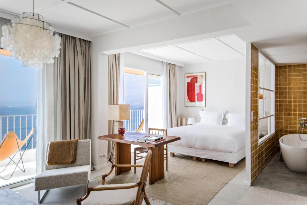圣拉斐尔Les Roches Rouges, a Beaumier hotel的酒店客房配有一张床、一张书桌和一个浴缸。