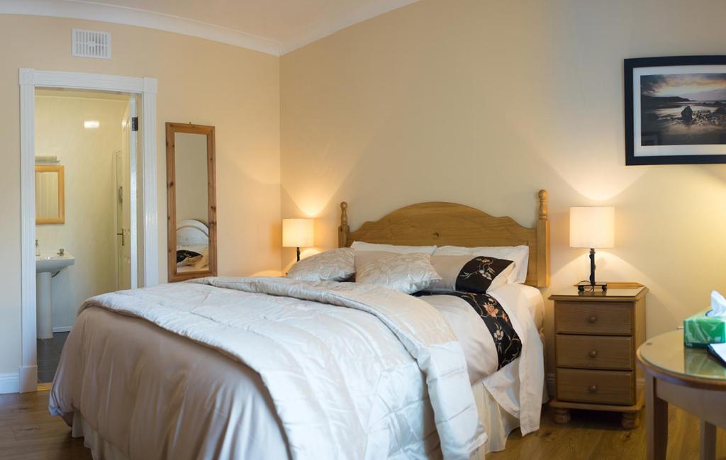 卡林福德格卢屋住宿加早餐酒店的一间卧室配有一张大床和一张带两盏灯的桌子。